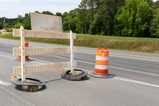 Rear view of a traffic barricade sign and orange and white traffic barrels, road closure, creative copy space, horizontal aspect