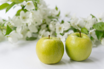 fresh ripe green apple with blossoms in background