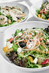 mixed fresh organic salads on white restaurant table