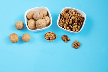 Walnut kernels in a bowls on a blue background.