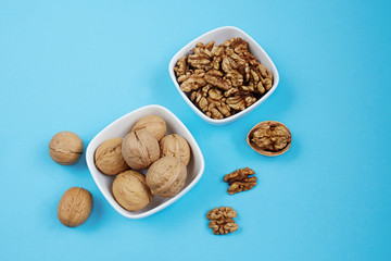 Walnut kernels in a bowls on a blue background.