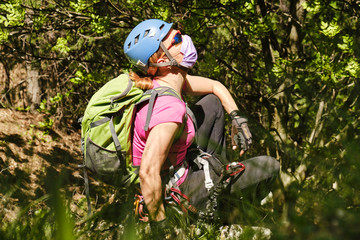 Woman mountaineer with helmet, backpack, and medical mask, enjoys the fresh nature air in a forest....
