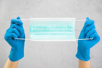 hands in medical gloves hold a medical mask