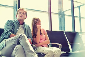 Mature man sitting with his daughter while waiting for their flight in airport
