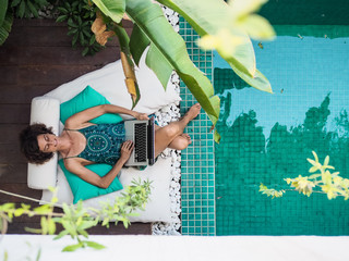bird view of a successful remote online working digital nomad women with curly hair with laptop...