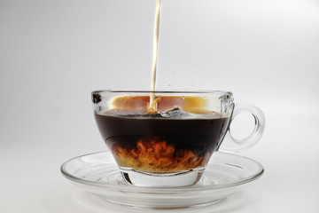 dark Coffee poring white milk dripping splash shadow liquid swirl in glass cup saucer on white background