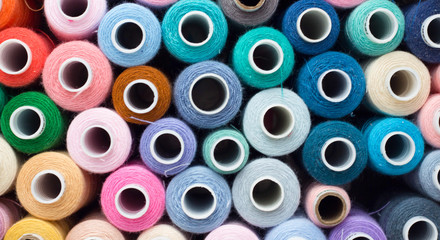 Sewing threads multi-colored background yellow, blue, pink, green, blue, beige closeup, banner, top view, flat lay, place for an inscription. threads for a sewing studio for sewing clothes