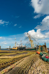 Fototapeta premium Dutch harbour with boats and fishing nets on a sunny summer day with a blue cloudy sky 