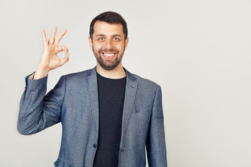 Young male businessman entrepreneur guaranteeing impeccable quality shows a confirmation gesture