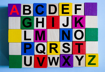 The letters of the alphabet are written on multi-colored cubes on a blue background.