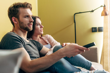 selective focus of bearded man holding remote controller and watching movie with girlfriend at home © LIGHTFIELD STUDIOS
