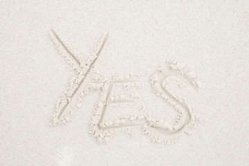 Concept: YES word on white clean sand.