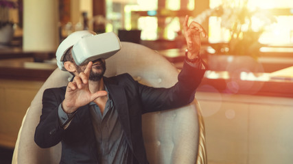 Stylish businessman in formal wear using VR glasses touching imaginary virtual display interface. Young handsome businessperson communicating by virtual reality