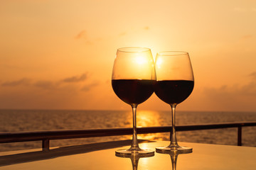 Glasses, red wine and tropical sunset with sea background, nobody.