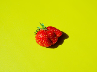 be different concept: wrong shaped strawberry on green background. horizontal, space for text