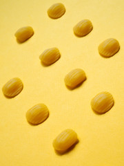 dry orecchiette pasta pattern. vertical, close up. yellow background