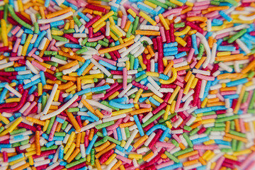 Fototapeta na wymiar Colorful sweet background with colorful sprinkles. Holiday treat. Cupcake and Ice cream topping. Sweet Texture. Sweet Background