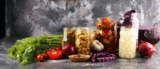 Preserves vegetables in glass jars. Pickled Cucumber, carrot, fermented cabbage and onions on rustic background