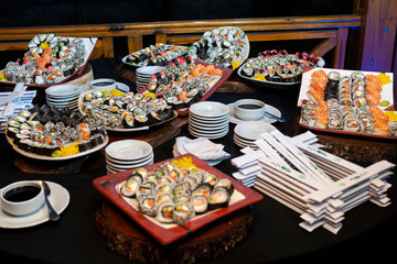 table with variety of fresh sushi on table at an event with its ingredients and utensils