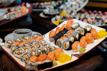 table with variety of fresh sushi on table at an event with its ingredients and utensils