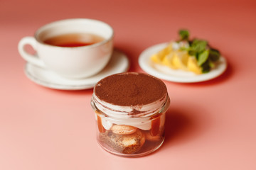 tiramisu, a cup of tea with chopped lemon on an orange background