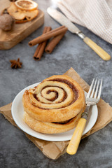 Cinnamon roll bun close up. Cinnamon swirl pastry for breakfast over grey background.