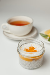 chia pudding with peach and coconut, tea with lemon on a white background