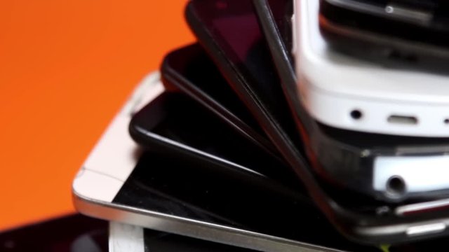 outdated and modern models of smartphones and mobile phones. a dirty, broken and old smartphone rotates on an orange background