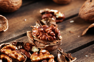 Walnut kernels and group of whole walnuts on rustic old table