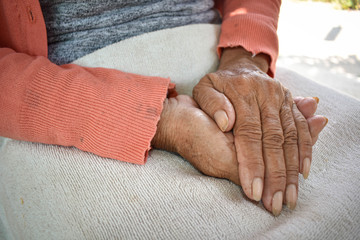 The hand of the sick old woman rests on the lap. Mental health care at home.