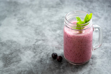 Fresh fruit berry smoothie in glass jar with mint leaves, grey background. Detox, summer drink.