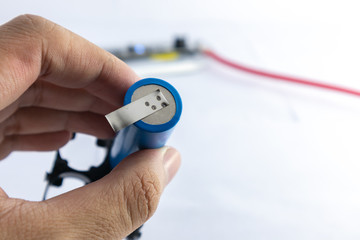 Spot welding blue lithium ion battery on hand with blurred background.