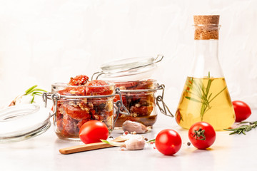 Sun dried tomatoes with garlic, oregano, olive oil in a jar on a light table, top view Food recipe background. Close up