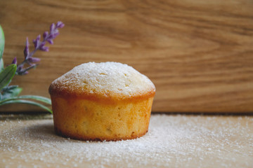 Close up picture of muffin cake with white powder on the top located on wooden background with...