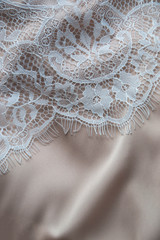 Close up picture of silk satin in nude shade and lace in white color on the side as copy space concept for weeding and fashion industry with retro style design for wallpaper and background for catalog