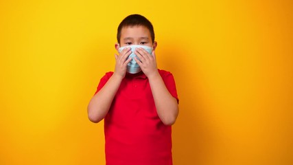 Asian boy wearing protective mask and showing thumb-up gesture on color background. Concept of epidemic
