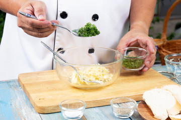 Chef putting minced parsley to bowl for cook garlic bread