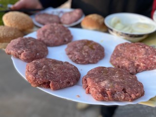 cooking a homemade burger outdoors. raw burger ingredients top view, outdoors homemade process of cooking on the yard during quarantine.