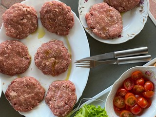 cooking a homemade burger outdoors. raw burger ingredients top view, outdoors homemade process of cooking on the yard during quarantine.