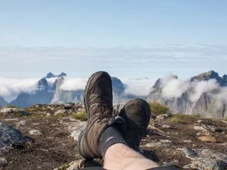 Fotobehang A hiker relaxes on the mountain ridge above Reine in Lofoten.  © Jack Mac