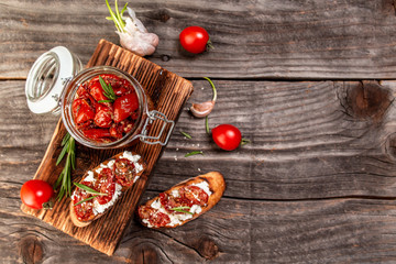 Traditional mediterranean cuisine. Delicious dried tomatoes in glass jar on wooden textured background. space for text. top view