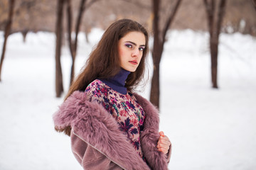 Portrait of a young beautiful woman in winter park