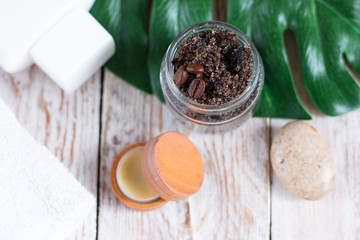 Handmade coffee scrub in a glass jar on a light wooden table. The concept of home care and spa treatments. View from above.