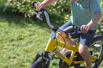 Boy on a yellow bicycles. A four year old boy rides barefoot on a bicycle on a summer day. Close-up. Toned