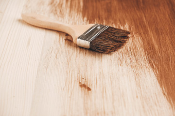 Brush with wooden handle and natural bristles against the background of painted brown wooden...
