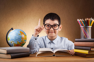 cute little boy schoolboy doing homework at a table with books. education. Junior School