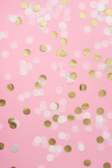 Paper confetti in pale pink, white and golden on pastel pink background, top view, selective
