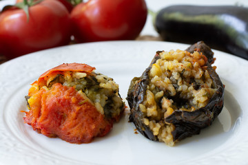 Traditional Azerbaijani eggplant dolma also called three sisters made vegan: an aubergine and a tomato stuffed with spicy rice and basil instead of the minced beef in a white plate
