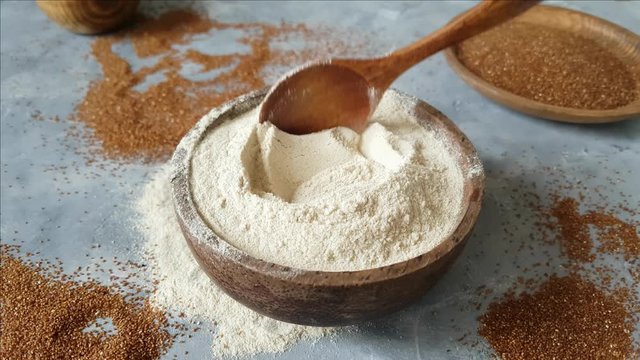 Teff flour in a bowl with a spoon and teff grain 