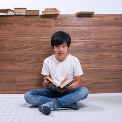 Young Asian boy reading book in library